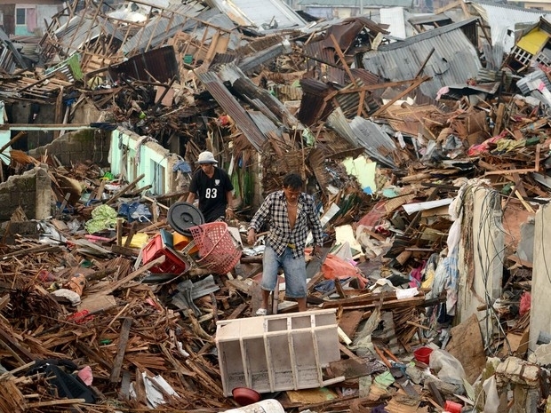 Homens procuram por material ainda utilizável em meio a escombros de casas destruídas pelo supertufão Haiyan em Tacloban